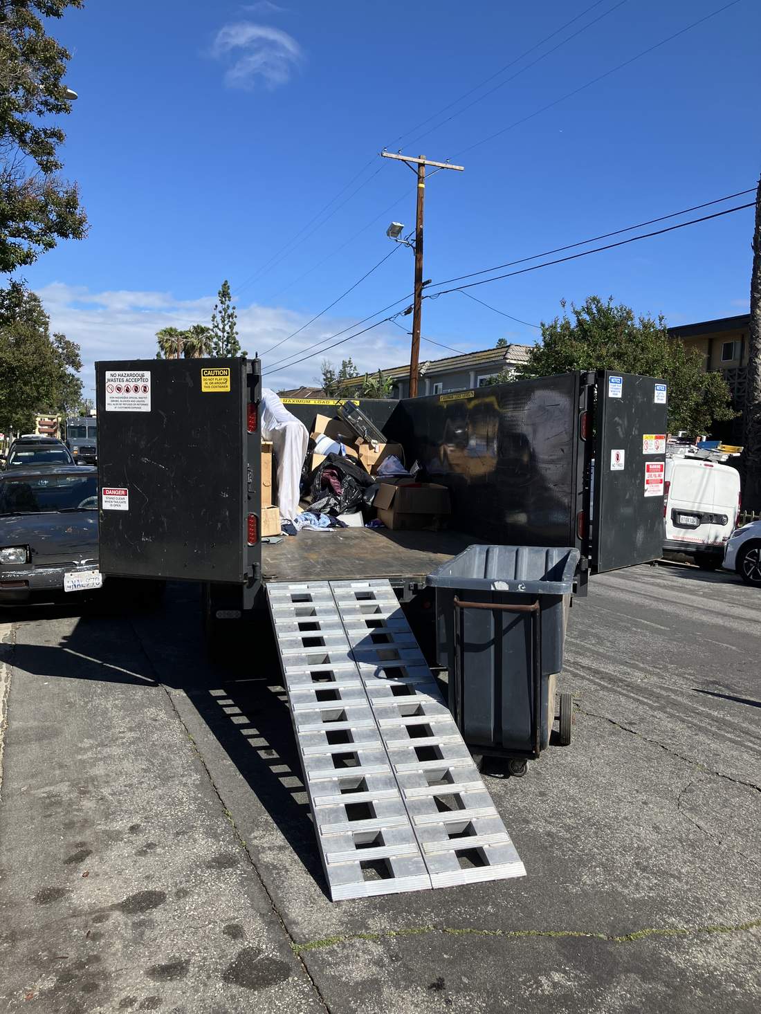 818 Junk trailer being loaded with boxes and a trash bin